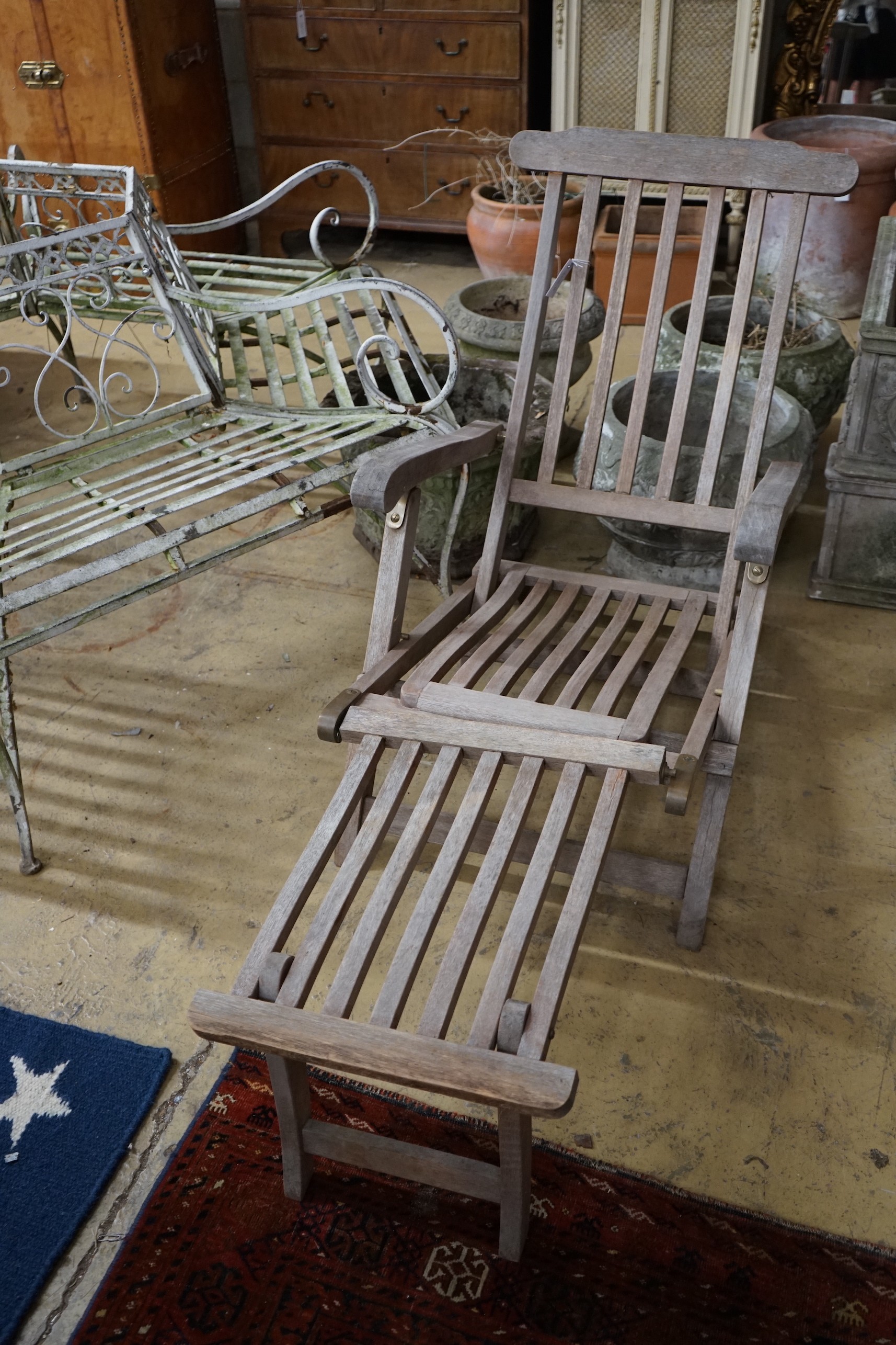 A weathered teak garden steamer chair with brass fittings